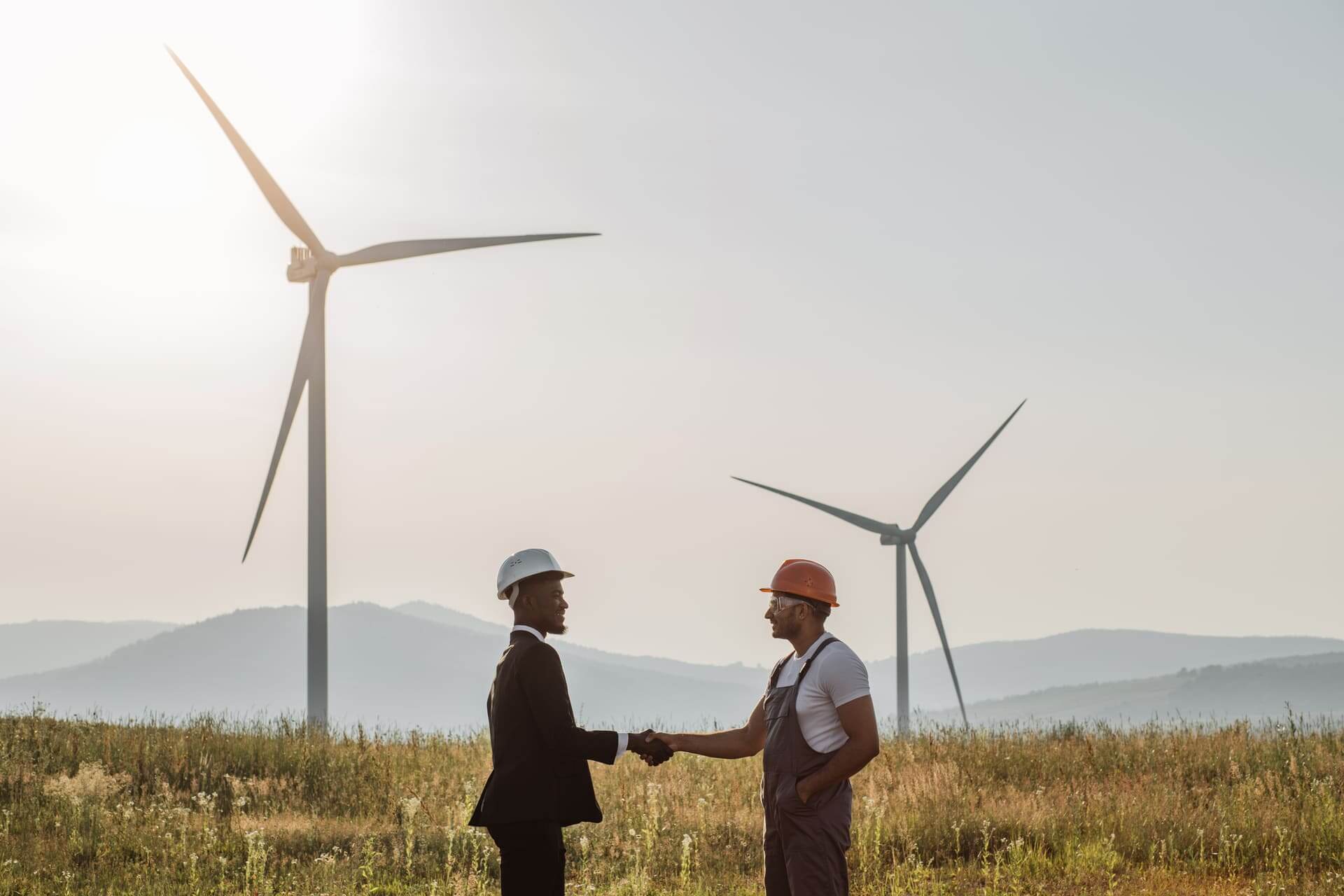 Clean Energy Trends: What\'s on the Horizon for GreenGlow colleagues shaking hands with wind turbines on bac 2022 04 27 03 47 37 utc